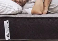 Man sleeping peacefully on a Sleep Firm mattress with white bedding in a cozy bedroom