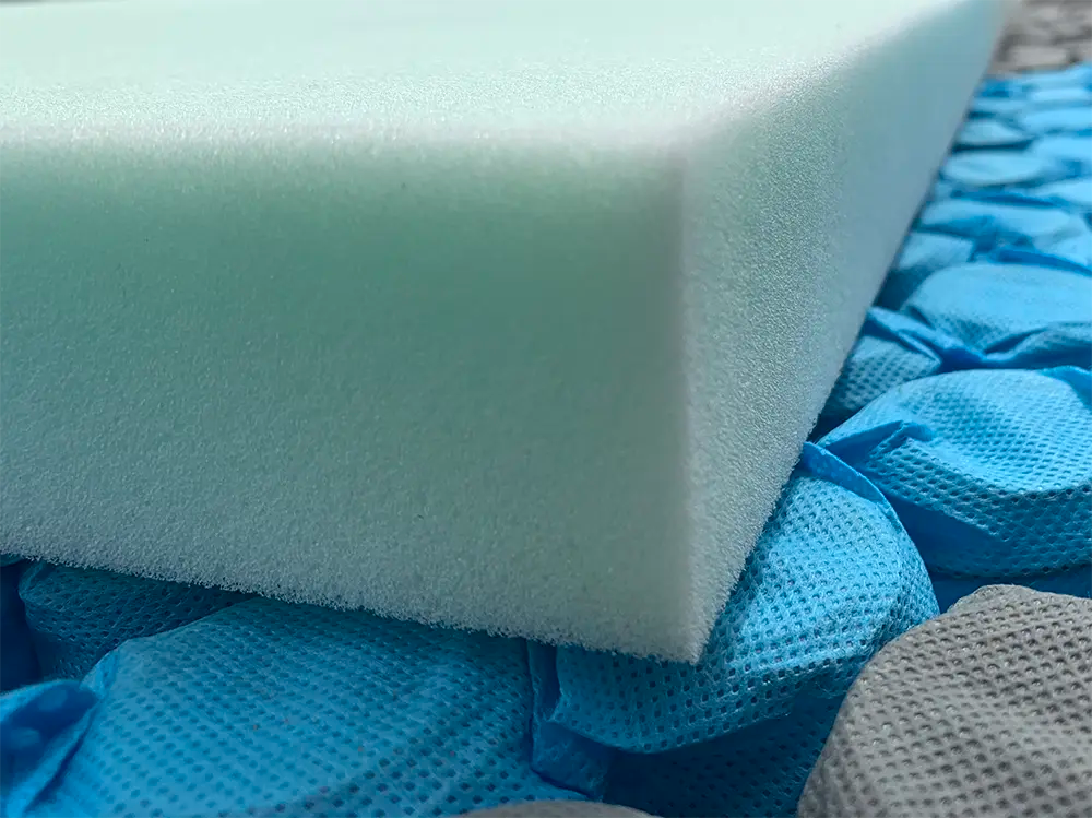 Close-up of white foam mattress topper on blue and gray pocket coil springs for mattress support