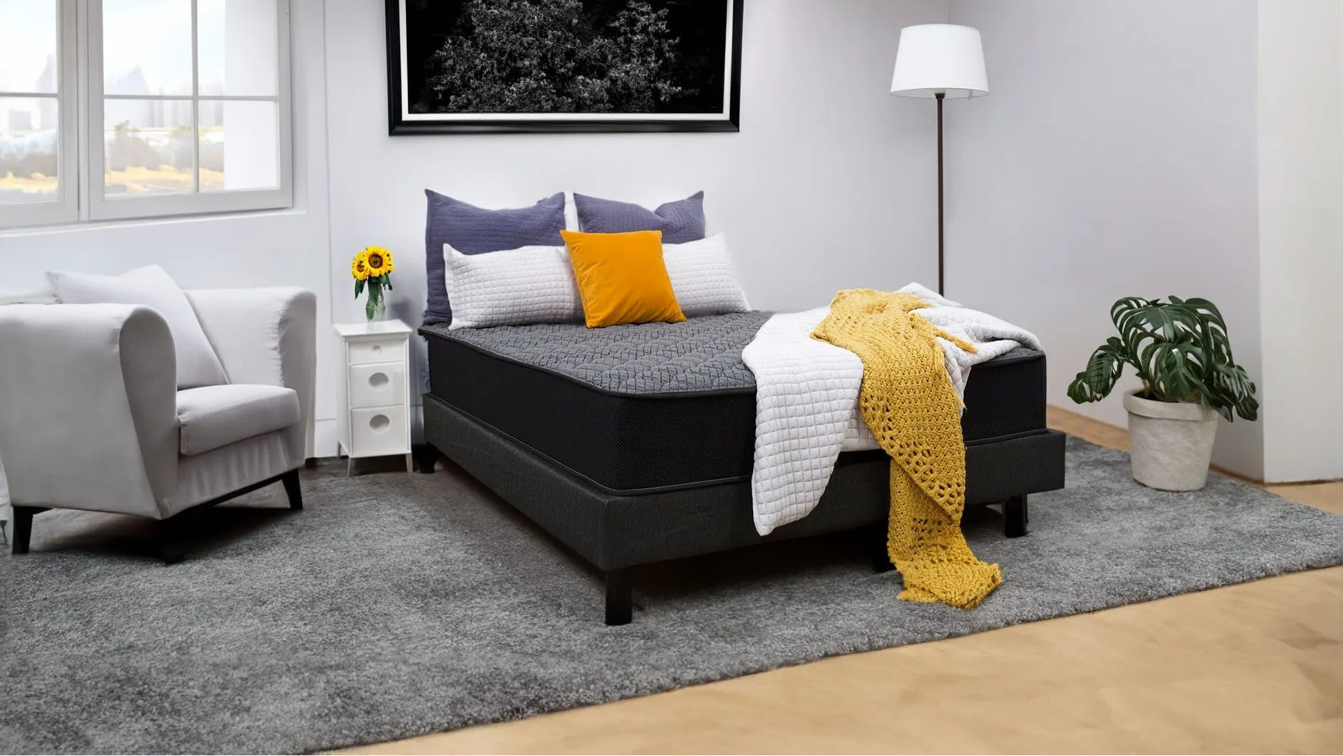 Modern bedroom with dark firm mattress, gray and yellow bedding, white armchair, and floor lamp