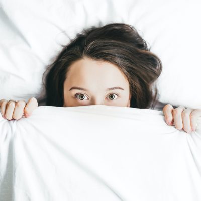 Woman peeking her head out from under the covers.
