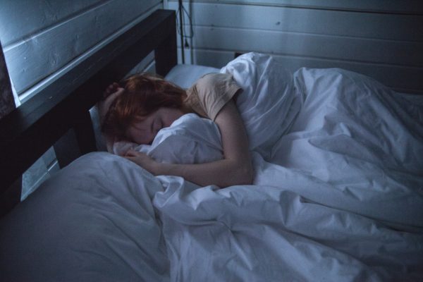 Girl asleep in bed hugging blanket.