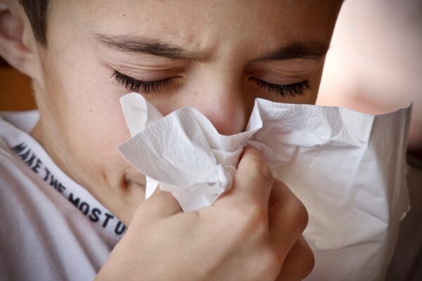 person sneezing into a tissue